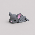 3D printed Teeny Bat figure in cool grey with pink inner ears and outstretched wings, lying down