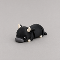 3D printed Teeny Bull figure in jet black with white horns, lying down