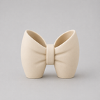 Cream-colored bow-shaped ceramic vase on a light gray background