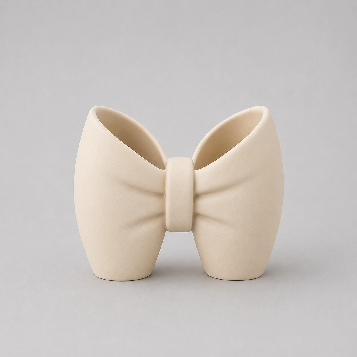 Cream-colored bow-shaped ceramic vase on a light gray background