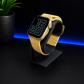 Smartwatch with a yellow braided band on a black stand against a dark background
