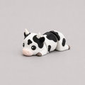 3D printed Teeny Cow figure in black and white with pink muzzle, lying down