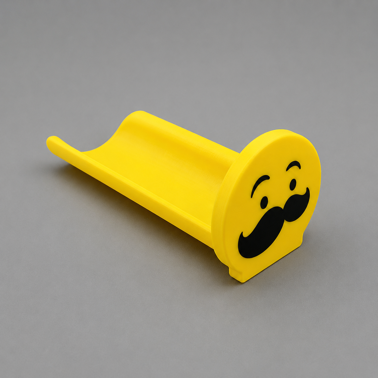 Yellow toy slide with a mustache design on a gray background