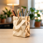 Pencil holder made from a brown paper bag filled with pens and pencils on a wooden surface.