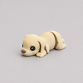 3D printed Teeny Dog figure in soft cream with floppy ears, lying down
