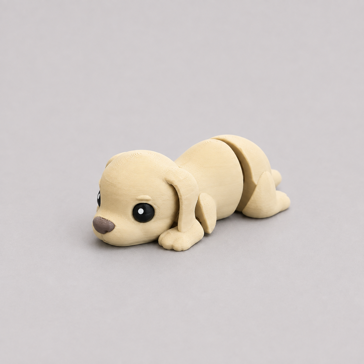 3D printed Teeny Dog figure in soft cream with floppy ears, lying down