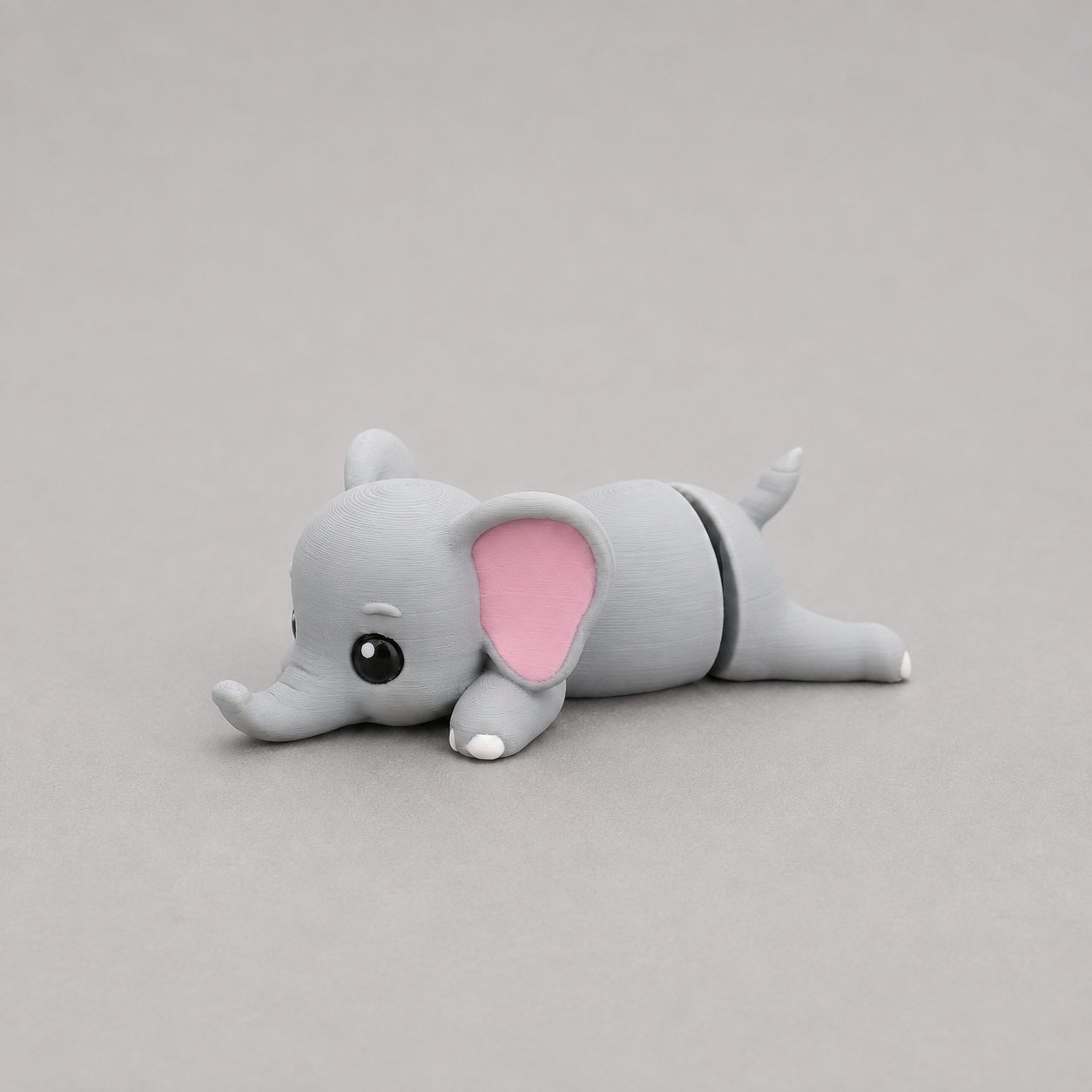 3D printed Teeny Elephant figure in soft grey with pink inner ears, lying down