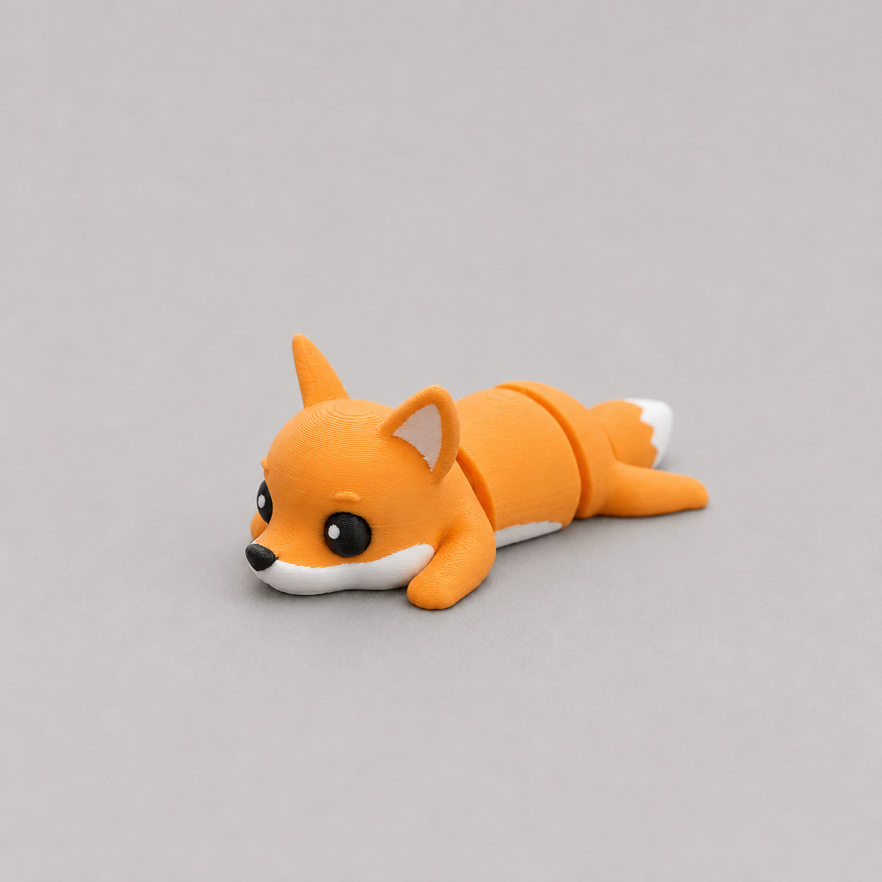 3D printed Teeny Fox figure in vivid orange with white muzzle and tail tip, lying down