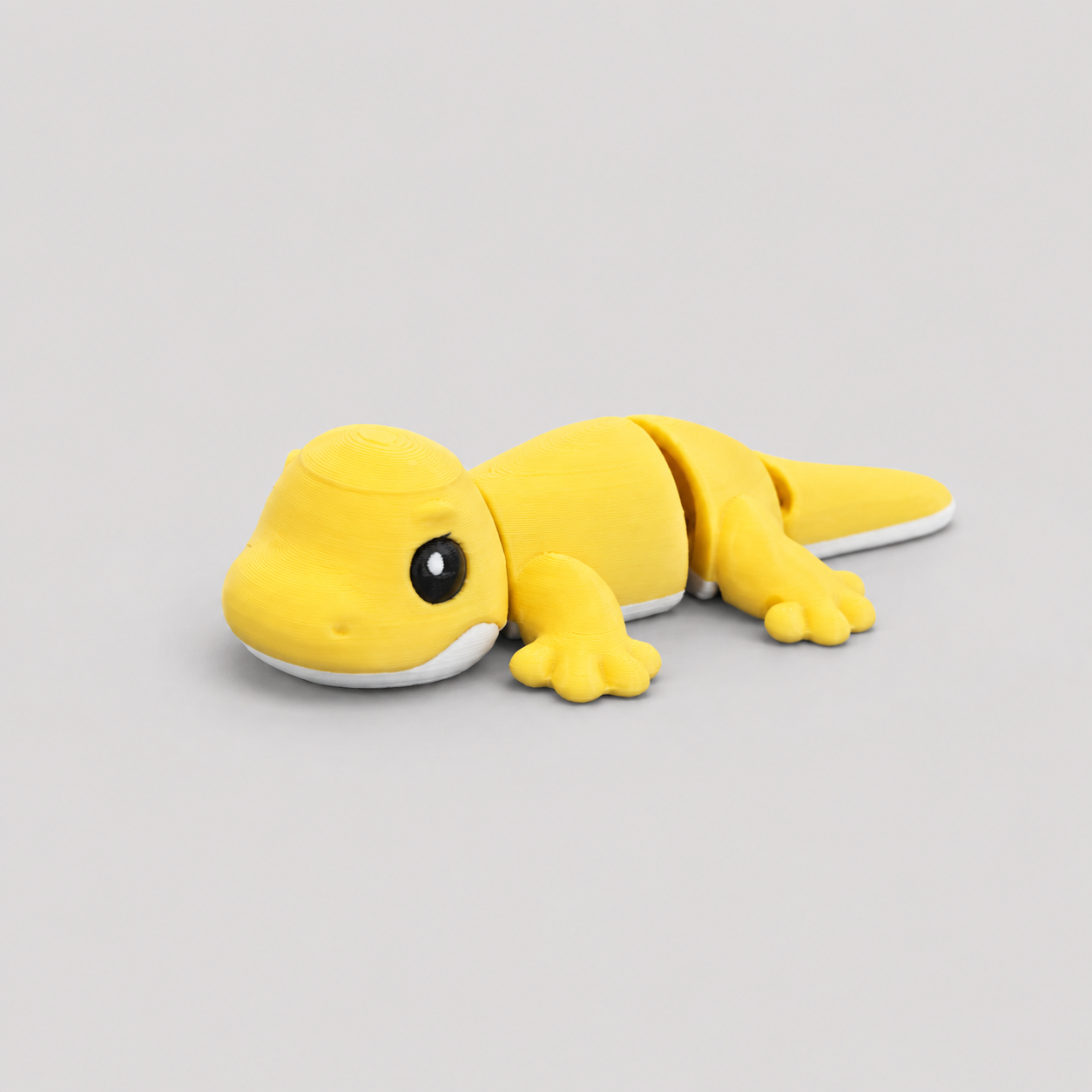 3D printed Teeny Gecko figure in vivid yellow with white underbelly, lying down