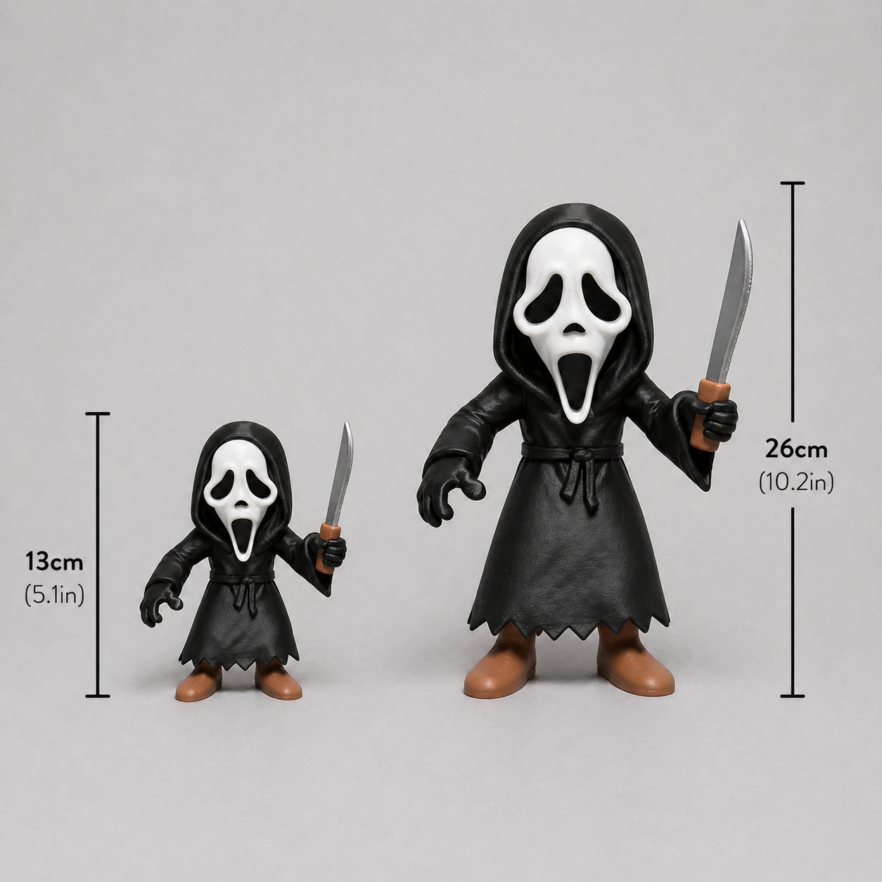 Two action figures with black cloaks and white masks, holding swords, with measurements indicated on a gray background.