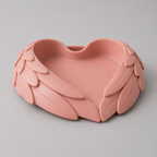 Pink heart-shaped dish with leaf-like designs on a gray background