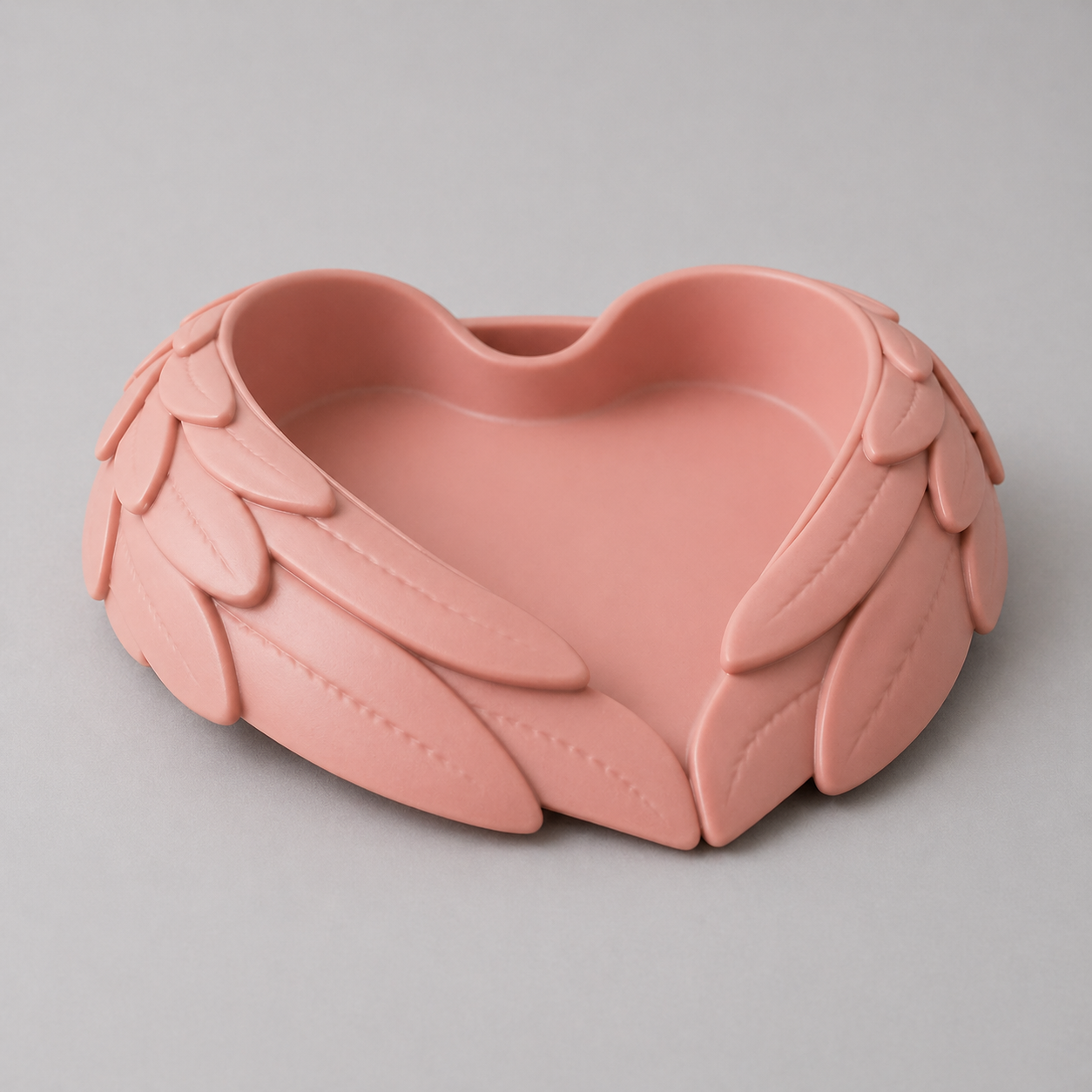 Pink heart-shaped dish with leaf-like designs on a gray background