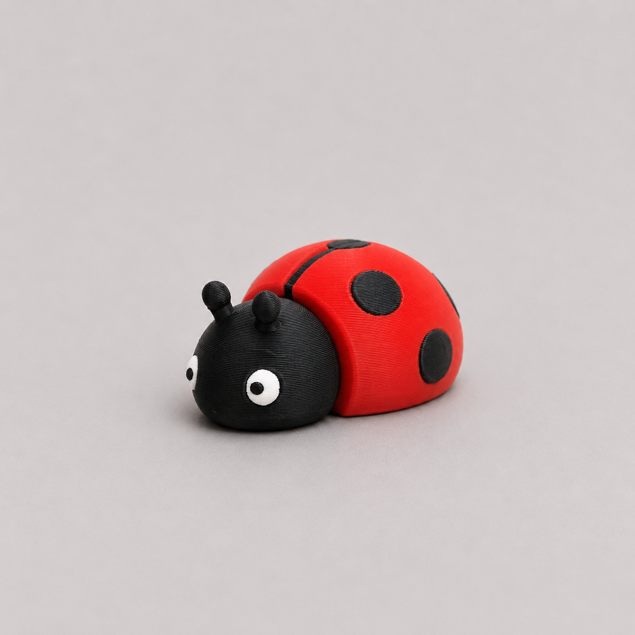 3D printed Teeny Ladybird figure in bold red with black spots, resting