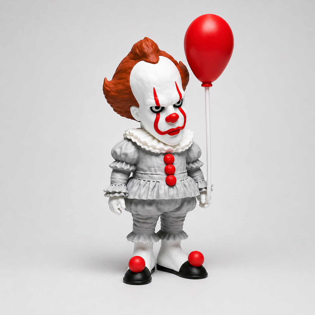 Clown figurine with red balloon on a gray background