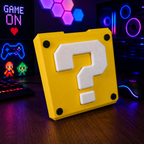 Yellow block with a white question mark on a desk in front of a computer setup with colorful lights.