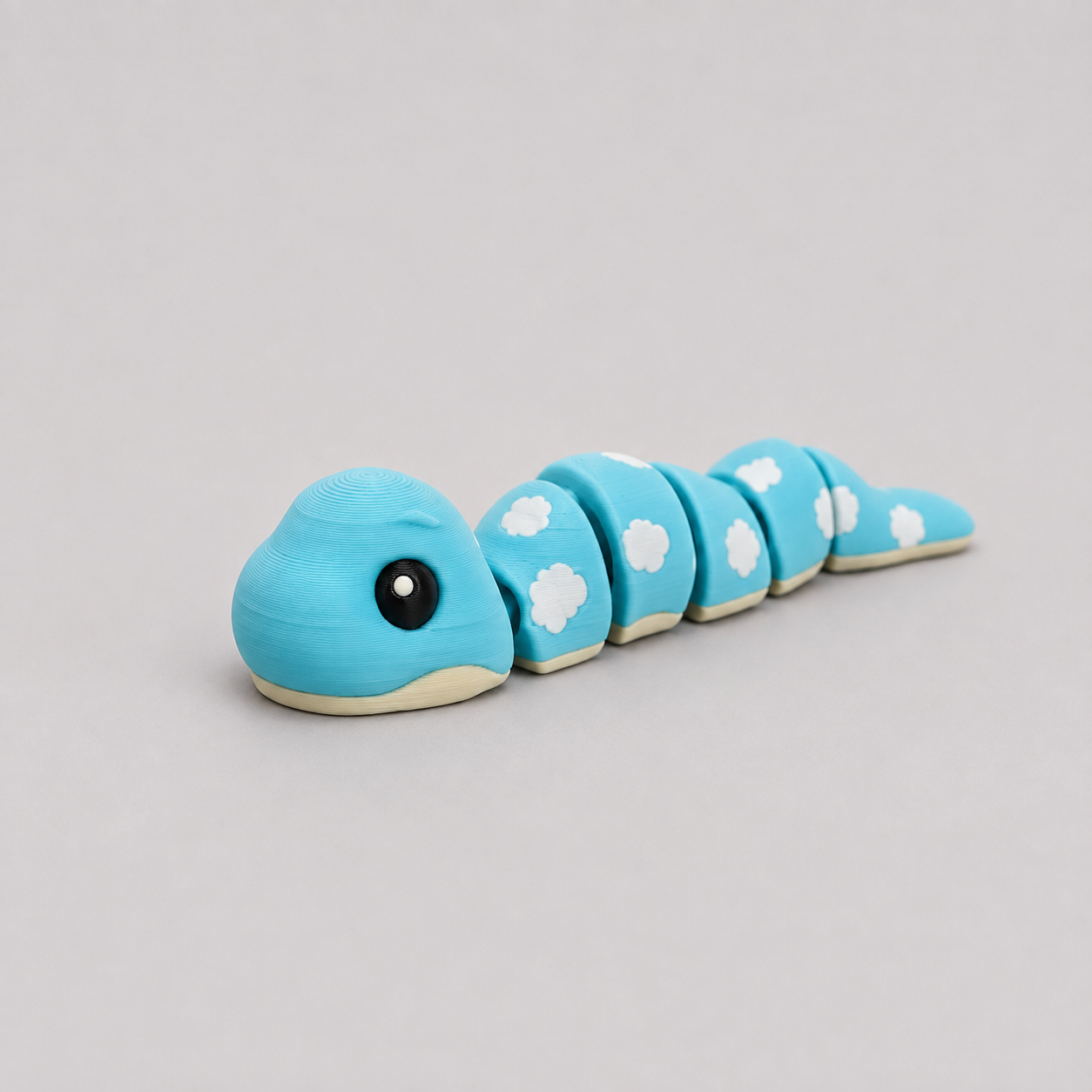 3D printed Teeny Snake figure in sky blue with white cloud markings, lying flat