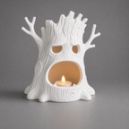 White ceramic tree-shaped candle holder with a lit candle inside on a gray background