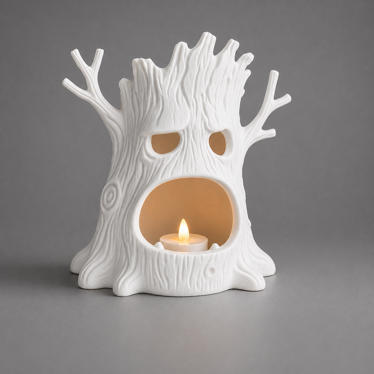 White ceramic tree-shaped candle holder with a lit candle inside on a gray background