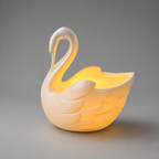 Swan-shaped lamp emitting a warm glow on a gray background