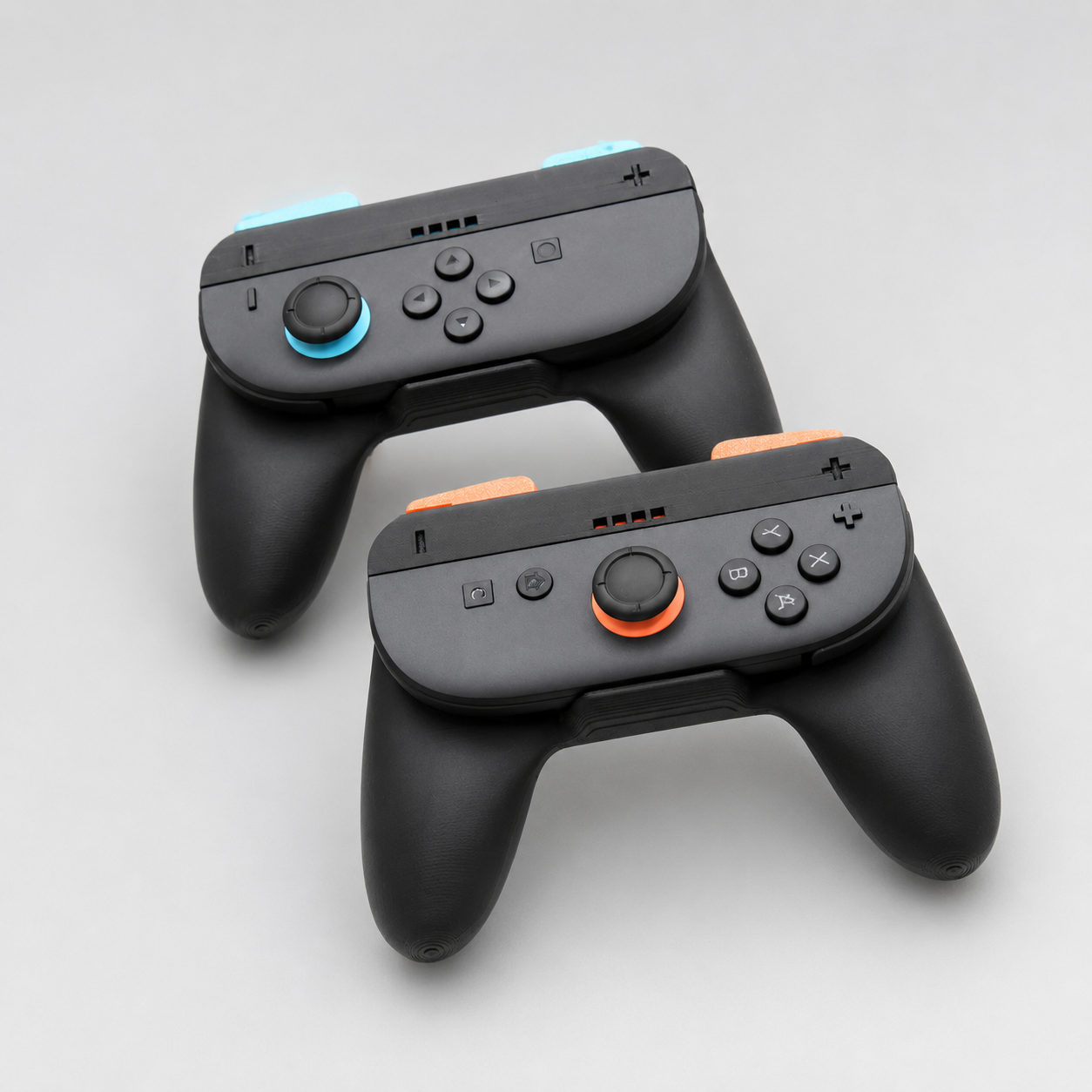Two black gaming controllers with orange accents on a light gray background