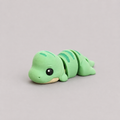 3D printed Teeny T-Rex figure in mint green with teal stripe markings, lying down
