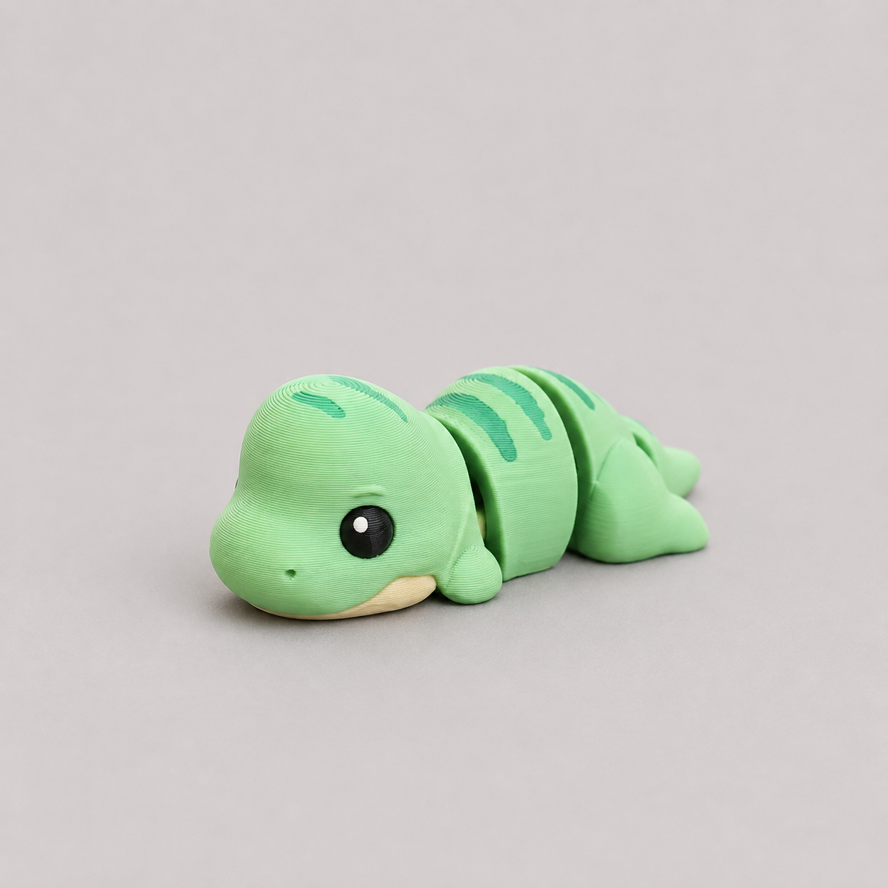 3D printed Teeny T-Rex figure in mint green with teal stripe markings, lying down
