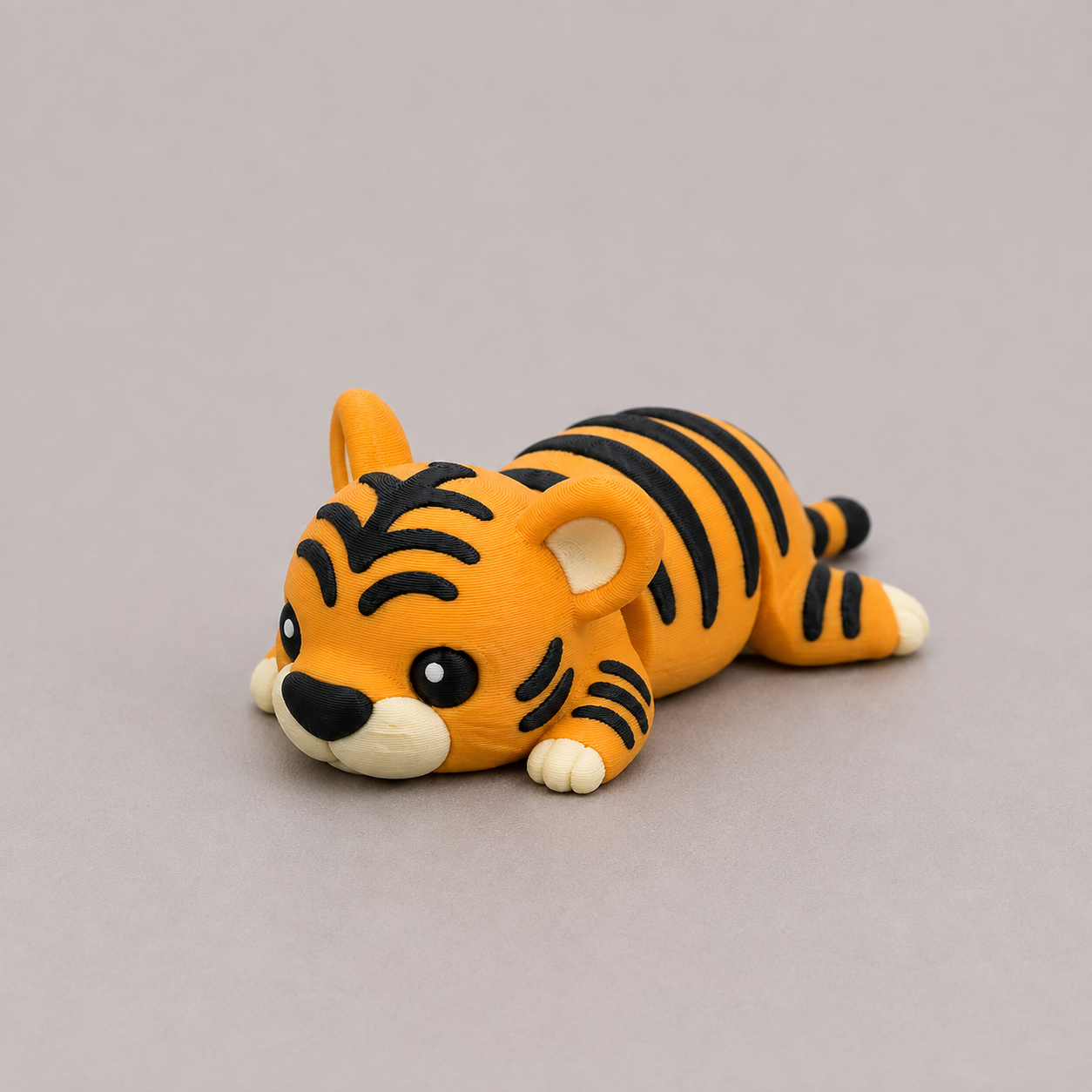 3D printed Teeny Tiger figure in bold orange with black stripes, lying down