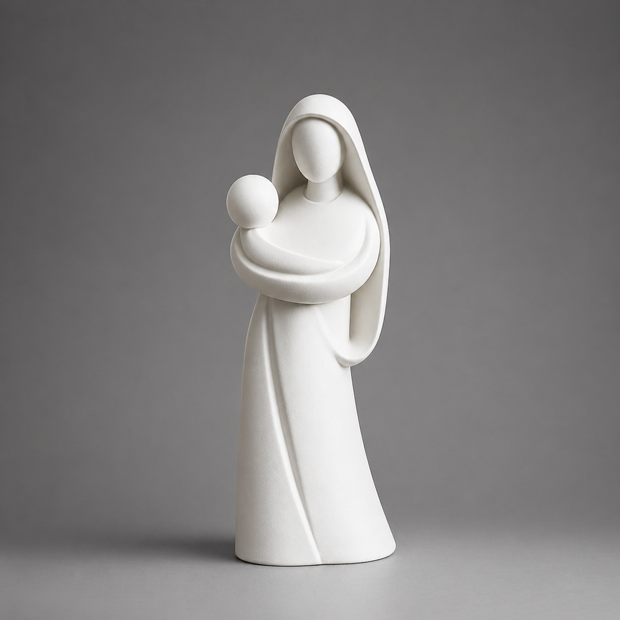 White ceramic statue of a mother holding a child against a gray background