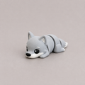 3D printed Teeny Wolf figure in cool grey with white muzzle, lying down