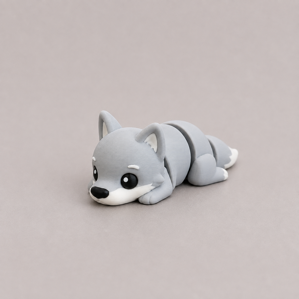 3D printed Teeny Wolf figure in cool grey with white muzzle, lying down